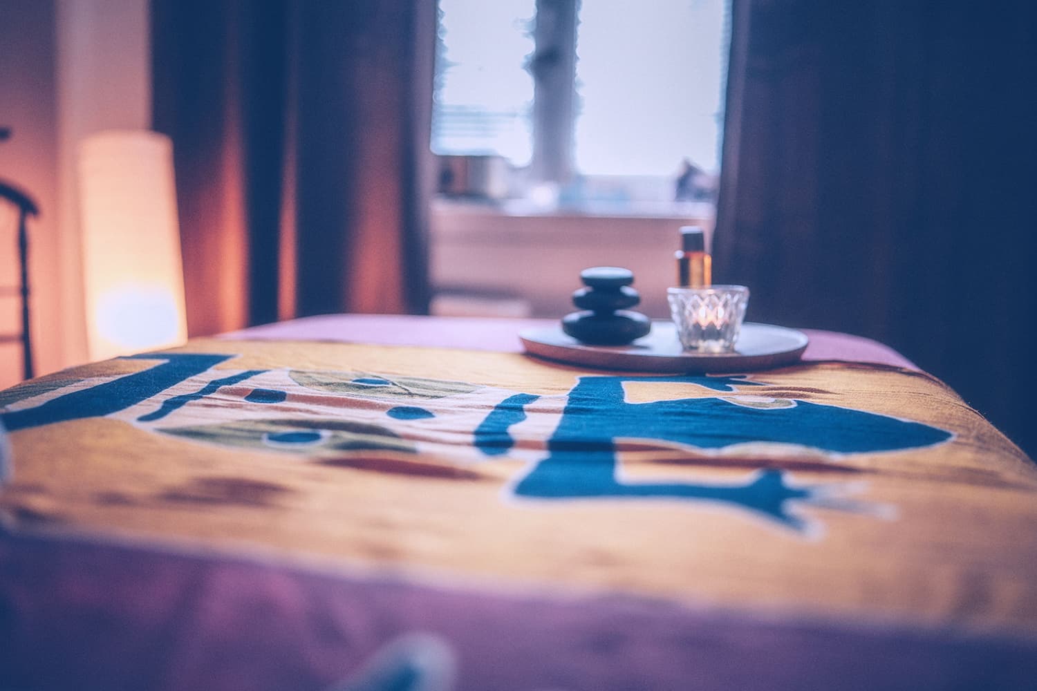 Masážní stůl s svíčkou, kameny a aromaterapií